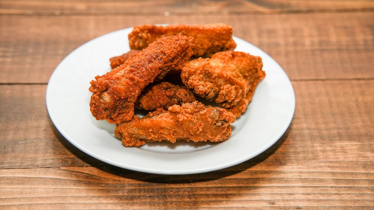 Golden brown crispy fried chicken wings served on a white plate, perfect for a tasty meal or snack.